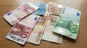 Banconote in euro usurate e piegate appoggiate su un tavolo, tra cui 10, 20, 50 e 100 euro