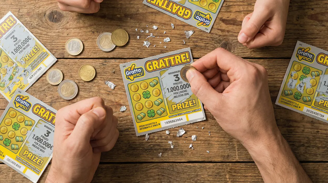 Mani che grattano un biglietto gratta e vinci vincente su un tavolo di legno con monete sparse