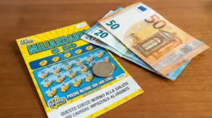 Biglietto gratta e vinci con moneta e banconote in euro su un tavolo, simbolo di vincita e tasse